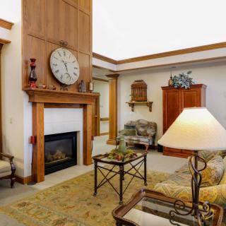 A cozy living room featuring a fireplace, large wall clock, and comfortable seating.
