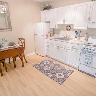 A cozy kitchen with white cabinets, a small dining table, and essential appliances.