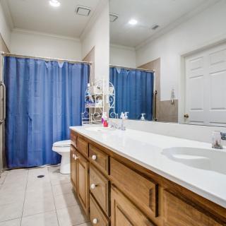 A spacious bathroom featuring a large mirror, wooden cabinets, and a blue shower curtain.