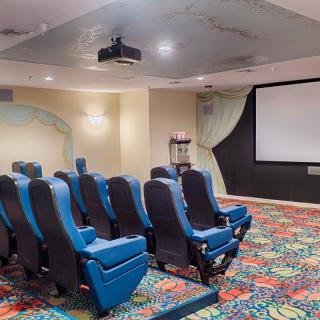 A cozy home theater room with blue seating and a projector screen.
