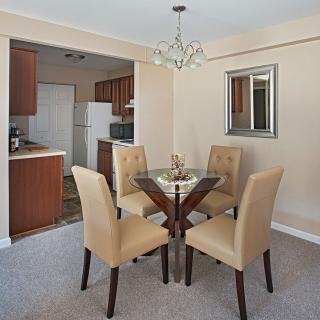 A cozy dining area with a round table and four upholstered chairs, accompanied by a chandelier and adjacent to the kitchen.