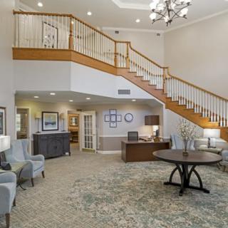 A well-lit lobby with a grand staircase, seating area, and chandelier.