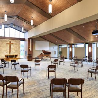 A serene interior of a modern church featuring spaced seating and wooden details.