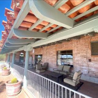 A sunny outdoor patio with comfortable seating and a brick wall backdrop.
