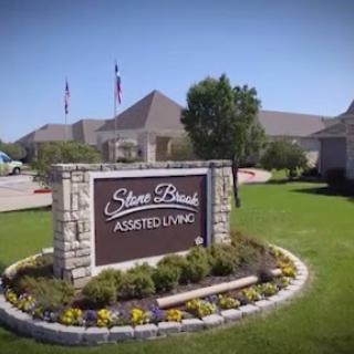 Welcoming sign for Stone Brook Assisted Living, featuring landscaped surroundings.