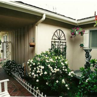 A charming exterior view of a house with a lush garden and blooming flowers.