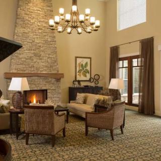A cozy living room with a stone fireplace, elegant chandelier, and comfortable seating.