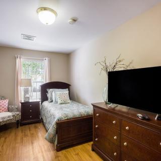 A cozy bedroom with a single bed, dresser, and a TV on top.
