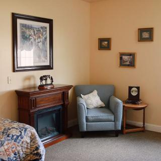 A cozy living room corner featuring an armchair, fireplace, and decorative wall art.