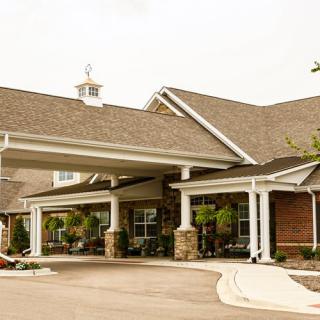 A view of a residential building with a covered entrance and landscaped driveway.
