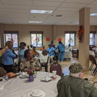 A lively community gathering taking place indoors, featuring seniors engaged in various activities.