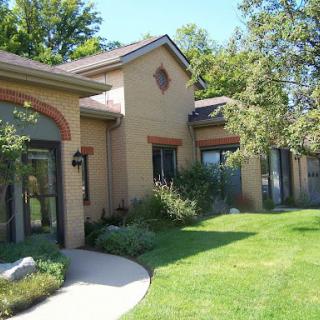 A beautifully landscaped residential house with a well-maintained lawn and trees.