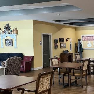 A cozy lounge area in a care facility, featuring comfortable seating and tables for socializing.