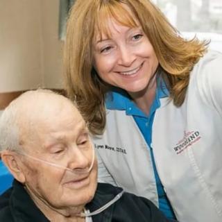 A healthcare professional smiling with an elderly patient receiving oxygen support.
