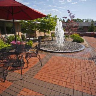 A serene patio area with a central fountain, surrounded by outdoor seating and lush greenery.