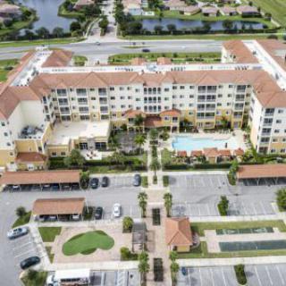 Aerial view of a residential apartment complex with a large central pool and landscaped surroundings.
