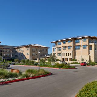 A view of modern residential buildings with well-maintained landscaping under a clear blue sky.