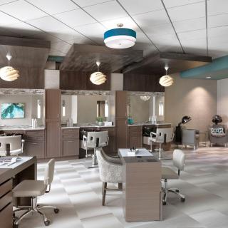 A modern beauty salon featuring sleek workstations, comfortable chairs, and stylish lighting.