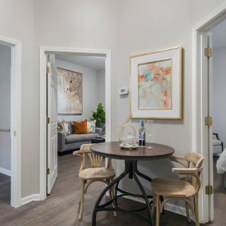 A cozy corner featuring a small round table with two chairs, adjacent to a living area with artwork on the walls.
