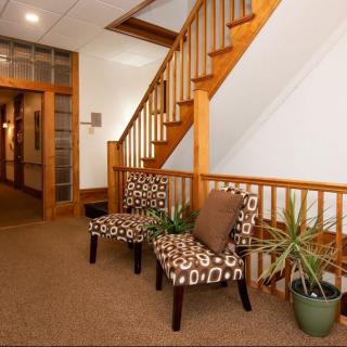 A cozy interior space featuring a wooden staircase, patterned chairs, and potted plants.