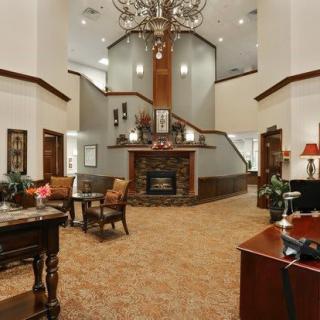 A spacious lobby with elegant decor, featuring a central chandelier and a fireplace.