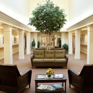 A well-furnished lobby with a central sofa, surrounding chairs, and an indoor tree.
