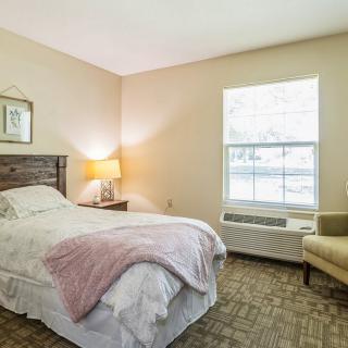 A cozy bedroom with a single bed, bedside lamp, and window.