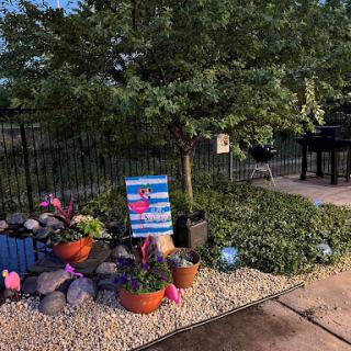 A beautifully arranged garden area featuring vibrant plants and decorative stones beside a barbecue grill.