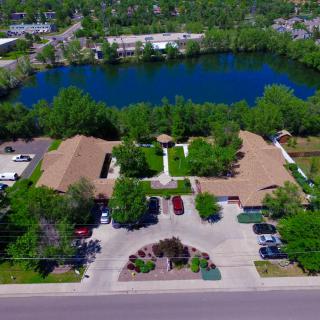 Aerial view of a complex with buildings surrounding a courtyard, adjacent to a scenic lake.