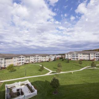 A residential area featuring multiple apartment buildings surrounded by green lawns and walkways under a cloudy sky.