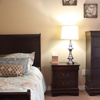 A cozy bedroom with a stylish bed, nightstand, and lamp.