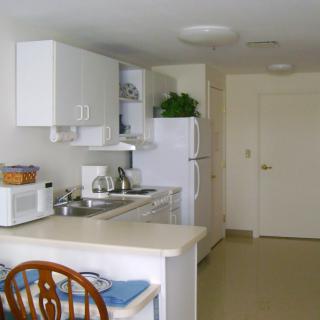 A compact modern kitchen with white cabinets and appliances.