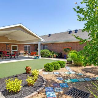 A view of a backyard featuring a covered patio area, landscaped garden, and outdoor seating.