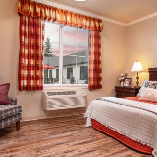 A cozy bedroom with warm-toned curtains and a neatly made bed.