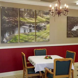 A cozy dining area featuring a table set for meals, complemented by wall art that evokes a serene natural landscape.
