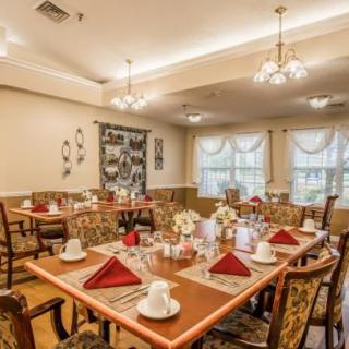 A well-decorated dining room with neatly arranged tables and chairs, featuring elegant lighting and tableware.