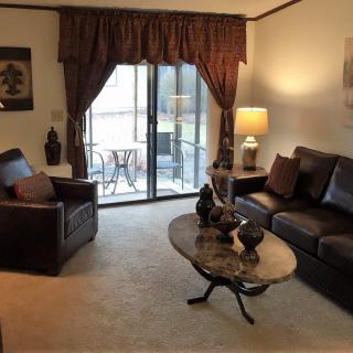 A cozy living room with a sofa, armchair, and coffee table, featuring warm lighting and elegant decor.