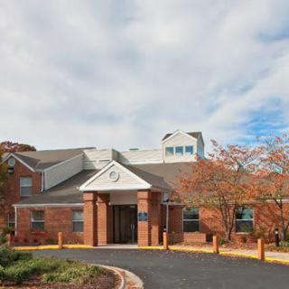 A brick building with an entrance, surrounded by trees and under a cloudy sky.