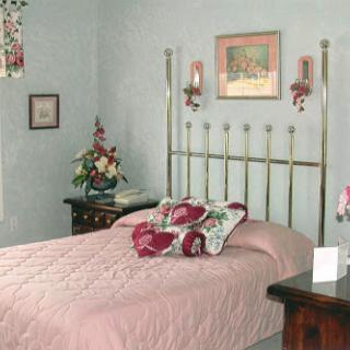 A cozy bedroom featuring a floral-themed bedspread and calming pastel wall color.