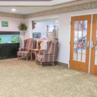 A cozy lobby featuring upholstered chairs, an aquarium, and decorative plants.
