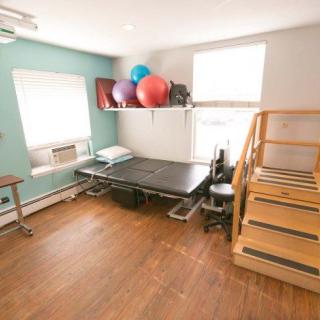 A rehabilitation room equipped with a therapy bed, stairs, and exercise balls.