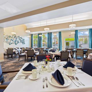 A beautifully set dining area in a restaurant with elegantly arranged tables and chairs, featuring neatly folded napkins.