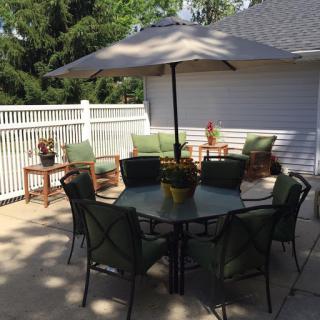 A cozy outdoor patio setup featuring a table with chairs and an umbrella for shade.