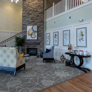 A cozy and modern living room featuring a stone fireplace, stylish furniture, and decorative artwork.