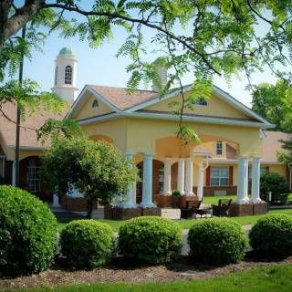 A charming residential house with a spacious porch surrounded by lush greenery.