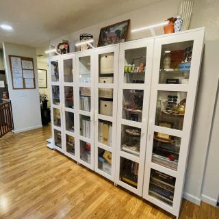 A well-organized bookshelf unit with glass doors in a neatly arranged room with wooden flooring.