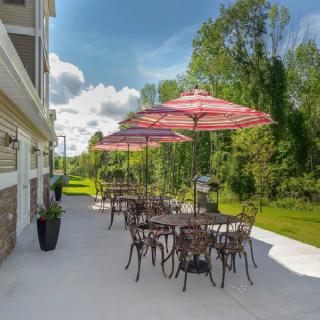 A sunny patio with tables, chairs, and umbrellas overlooking a lush green landscape.