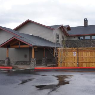 A residential building with a wooden fence and paved driveway.