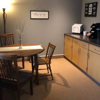 A cozy dining area with a wooden table and chairs, accompanied by cabinets and a lamp.