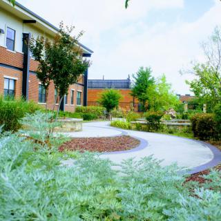 A scenic view of a brick building surrounded by lush greenery and a winding pathway.